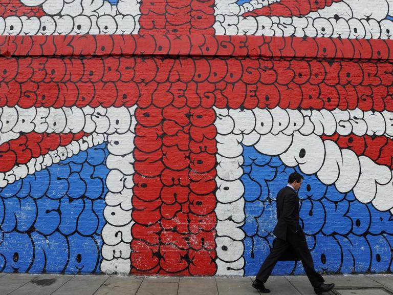 Ein Mann läuft an einem Grafitti, das die britische Flagge zeigt, vorbei.