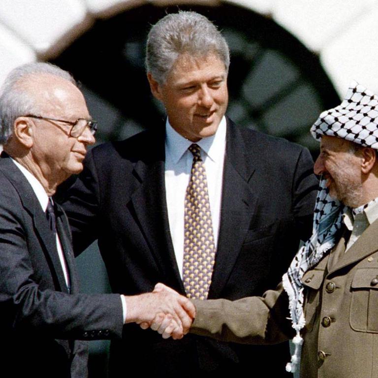 Jitzchak Rabin (li.) und Jassir Arafat (re.) reichen sich in Washington die Hand anlässlich der Unterzeichnung des Gaza-Jericho-Abkommens, in der Mitte US-Präsident Bill Clinton