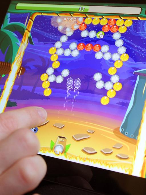 Eine Hand streicht auf einem Tablet-Computer über die Oberfläche eines Spiels.