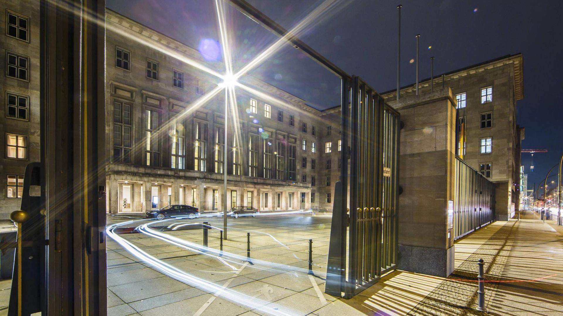 Eine Limousine fährt bei Nacht aus dem Haupteingang des Finanzministeriums in Berlin.