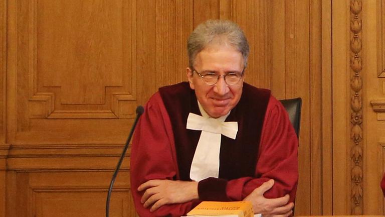 Kurt Graulich sitzt in roter Robe hinter der Richterbank in einem Gerichtssaal.