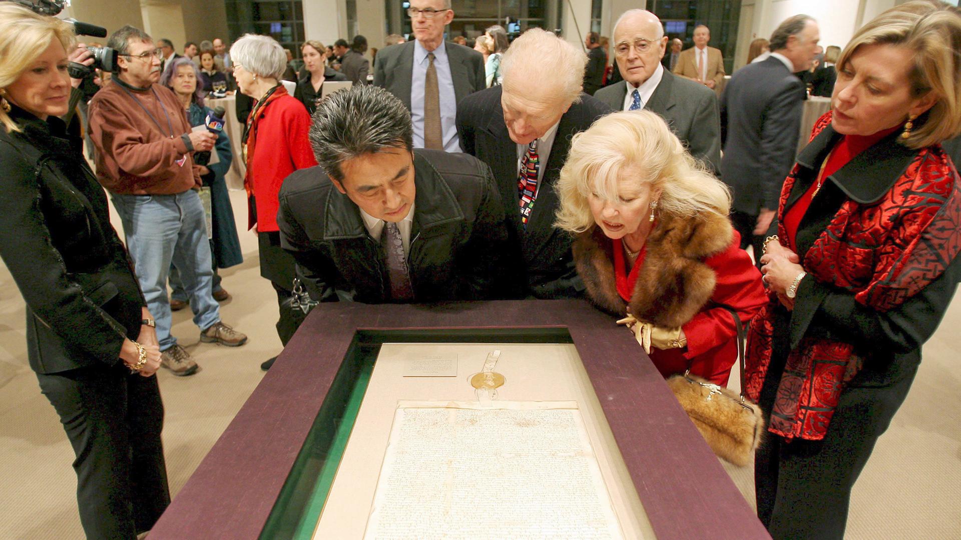 Besucher des Auktionshauses Sotheby's in New York beugen sich am 18.12.2007 über ein Exemplar der Magna Charta, bevor es dort versteigert wird.