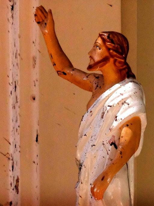 Blutflecken sind an der Wand und auf einer Jesus Christus-Figur in der durch eine Explosion beschädigte St.-Sebastians-Kirche.