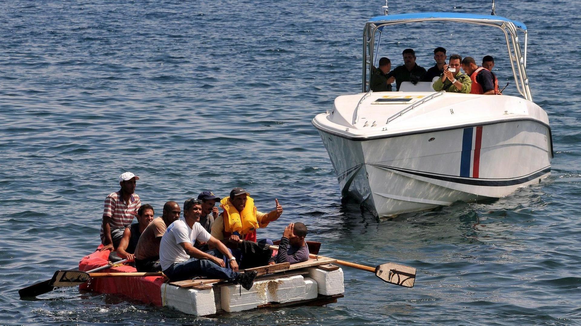 Sie sehen kubanische Flüchtlinge auf einem Floß und ein Boot der kubanischen Küstenwache.