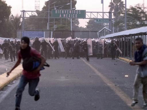 Migranten aus Mittelamerika laufen während Zusammenstößen mit der Polizei nahe der Grenze zwischen Guatemala und Mexiko vor mexikanischen Beamten weg.