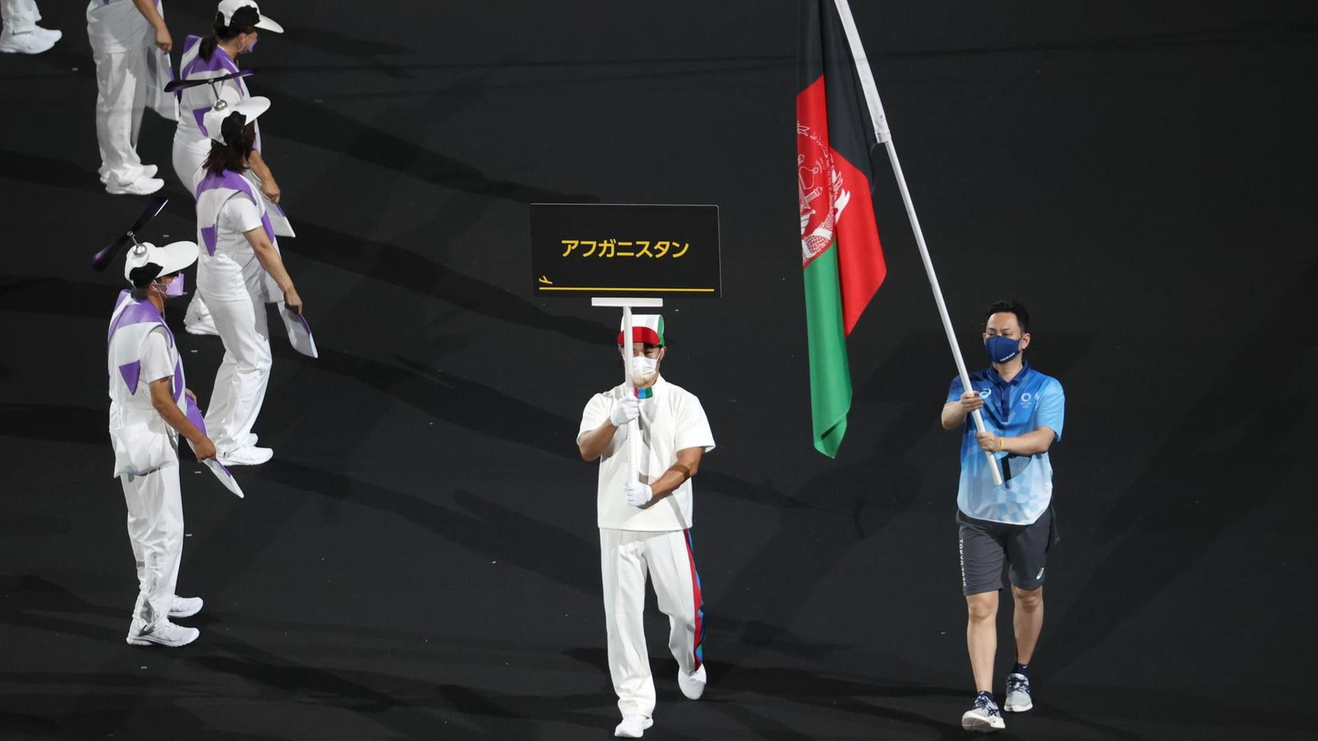 Paralympics in Tokio: Eröffnungsfeier im Olympiastadion. Das Flagge Afghanistans wird von Volonteers bei den Paralympics präsentiert.
