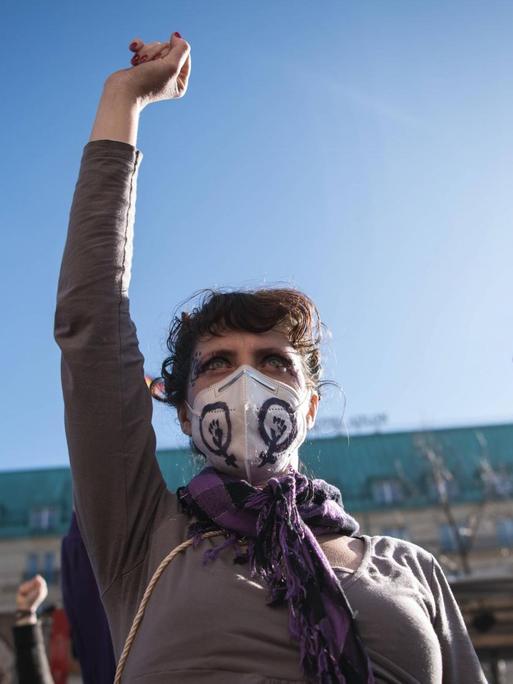 Demonstrantinnen auf der Frauentagsdemo am 8. März 2021 vor dem Brandenburger Tor strecken die Faeuste in die Luft