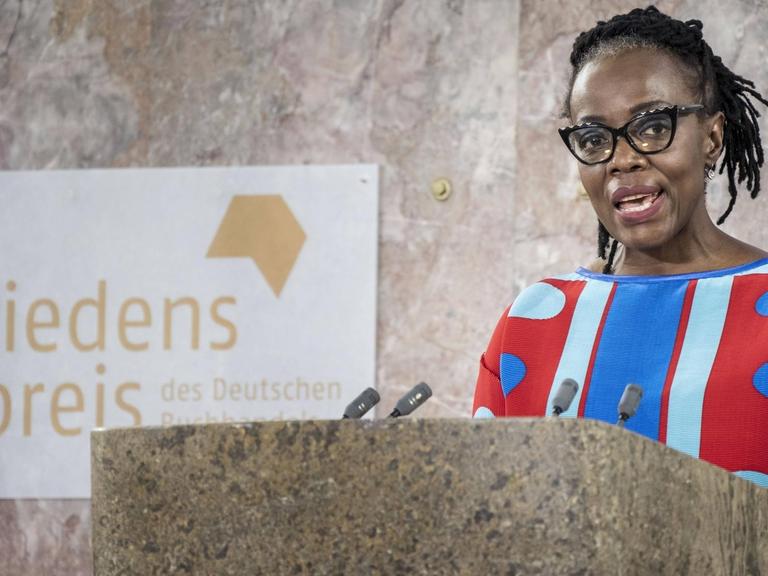 Tsitsi Dangarembga steht an einem Pult. Sie spricht in ein Miktofon.