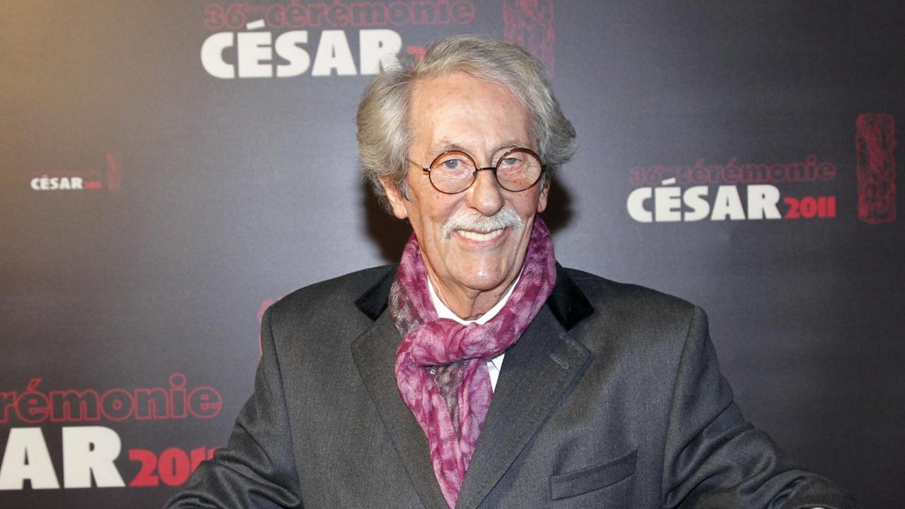Das Bild zeigt den gestorbenen französischen Schauspieler Jean Rochefort bei der "César"-Preisverleihung im Februar 2011. Er steht lächelnd vor einer dunklen Wand mit "César"-Schriftzügen.