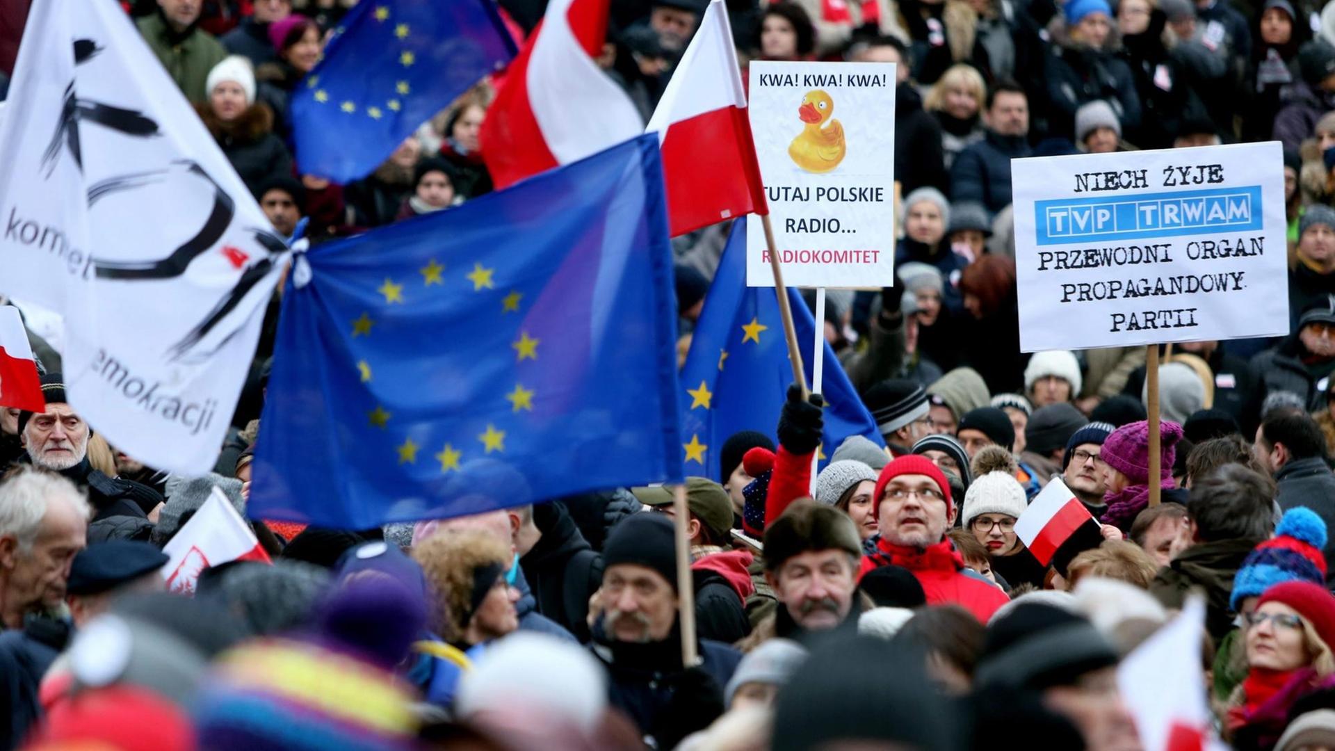 Viele Menschen dichtgedrängt, sie halten Plakate und polnische sowie EU-Flaggen.