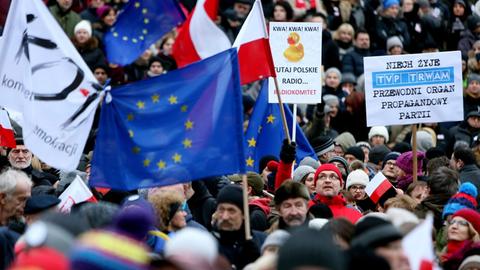 Viele Menschen dichtgedrängt, sie halten Plakate und polnische sowie EU-Flaggen.