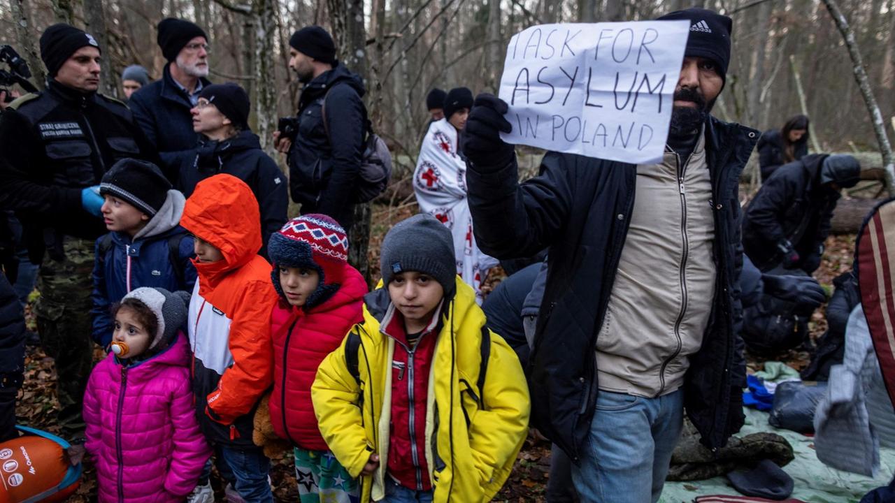 Kurdische Familie aus dem Irak im polnischen Narewka nahe der Grenze zu Belarus mit einem Schild "Ich suche Asyl in Polen"