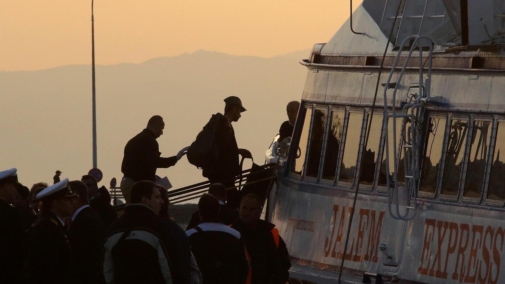 Man sieht im Gegenlicht der untergehenden Sonne, wie die Flüchtlinge über die Gangway ins Boot laufen.