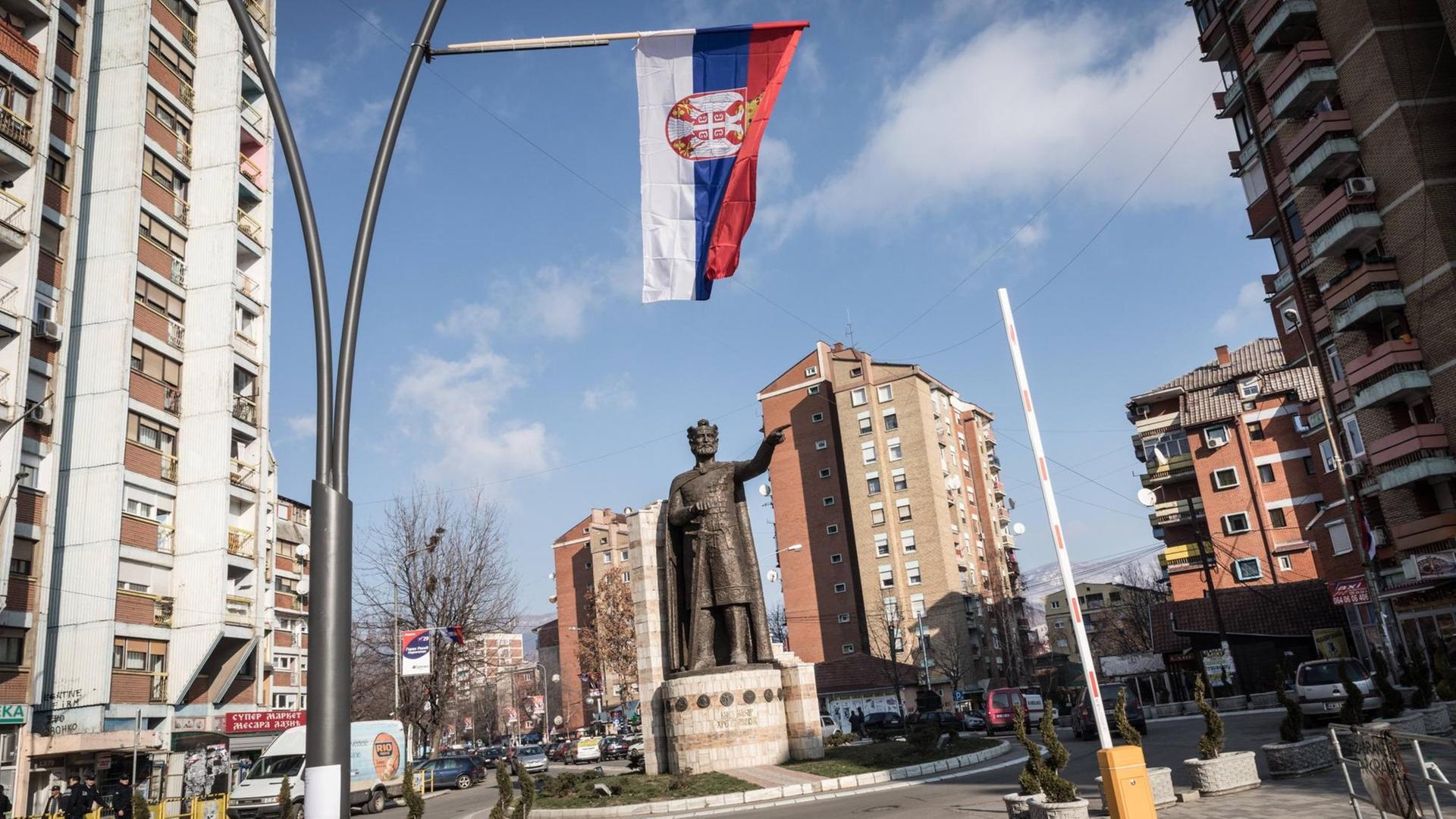 Straßenszene aus der Stadt Mitrovica im Kosovo: An einer Straßenlaterne hängt eine serbische Flagge.