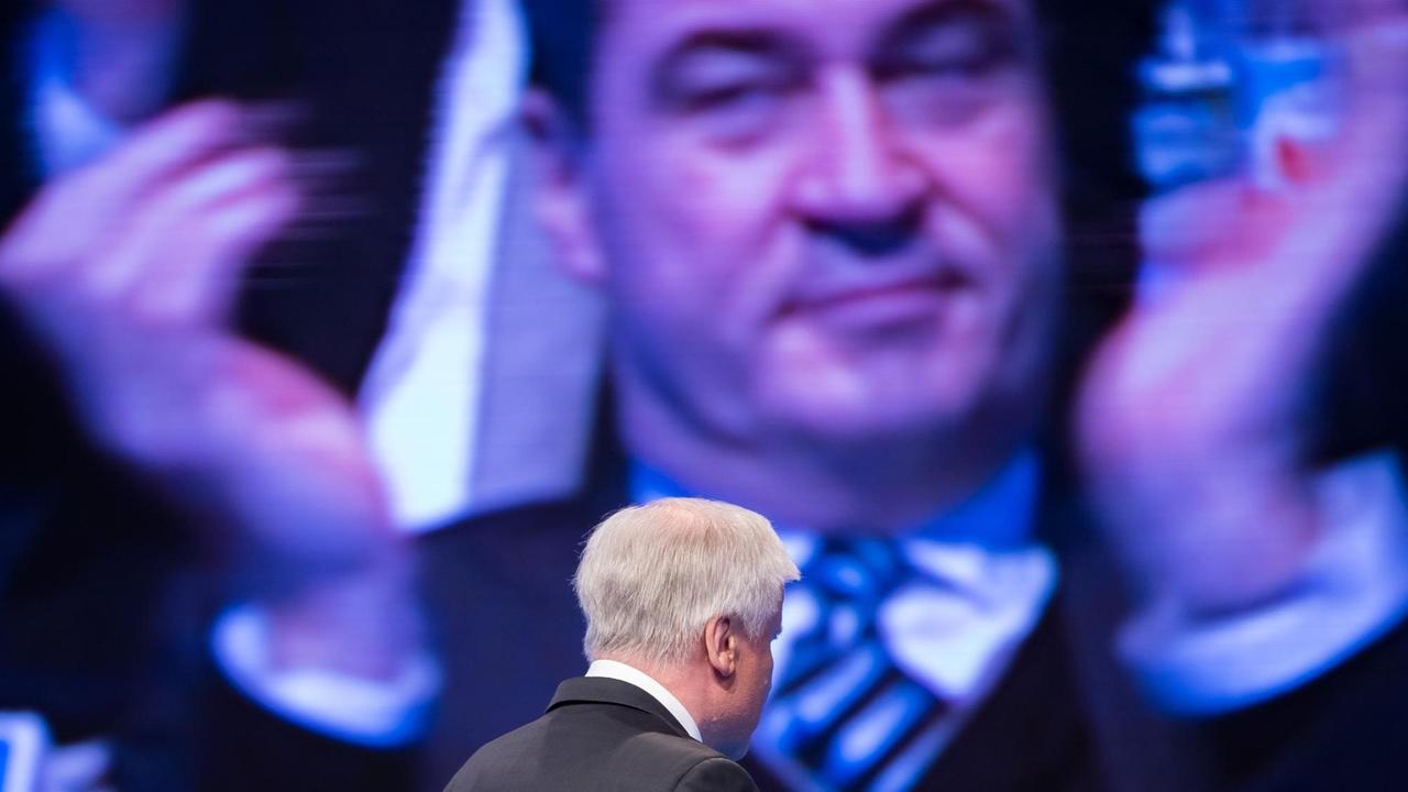 Der CSU-Parteivorsitzende Horst Seehofer verlässt während eines Parteitags die Bühne, auf dem Bildschirm im Hintergrund ist der applaudierende bayerische Finanzminister Markus Söder zu sehen.
