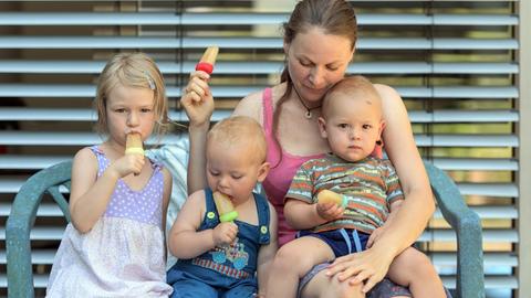 Eine Mutter mit drei Kindern sitzt in Freiburg im Breisgau im Garten und isst Eis