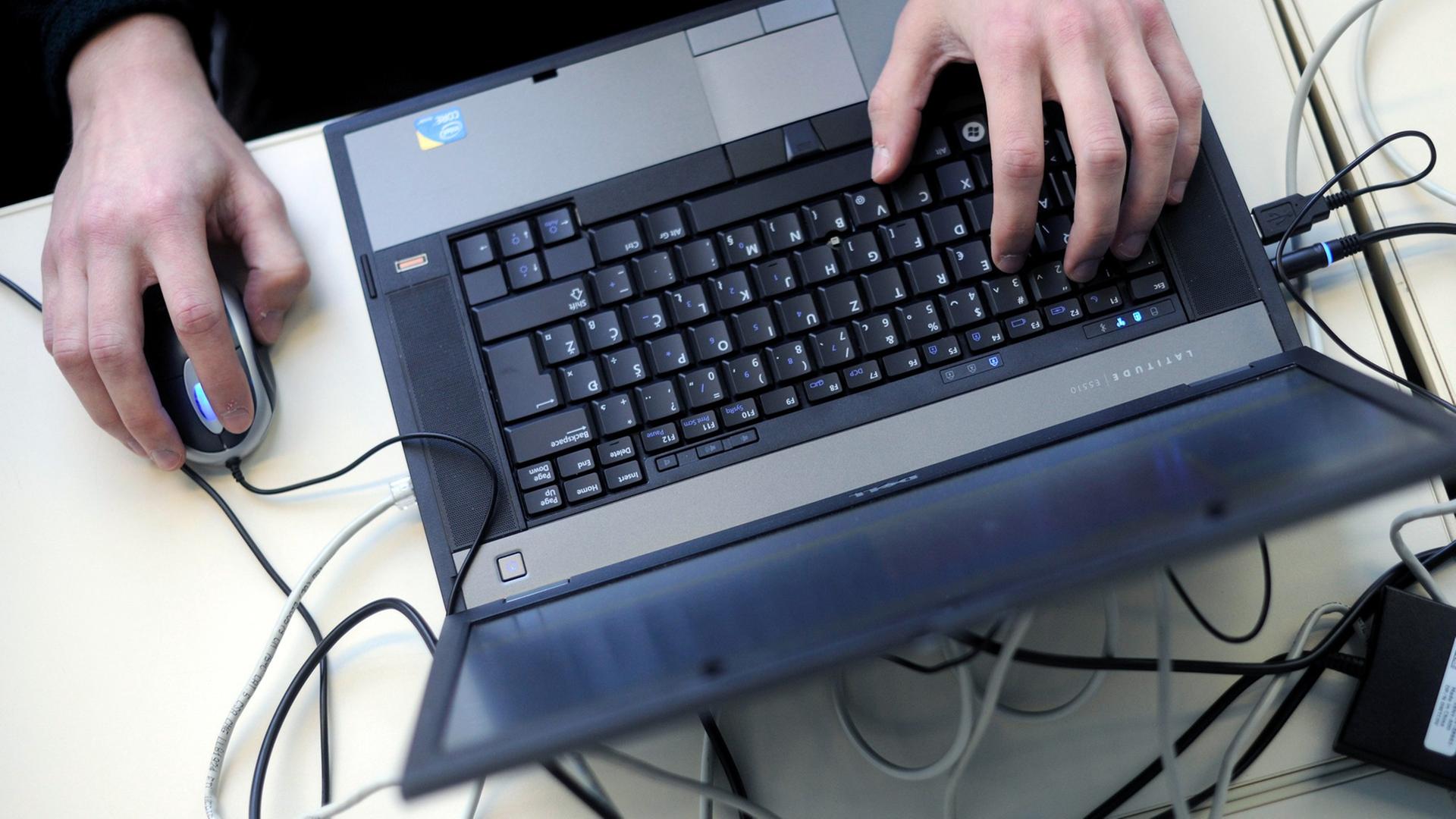 Eine Person bedient einen Laptop mit einer Mouse.