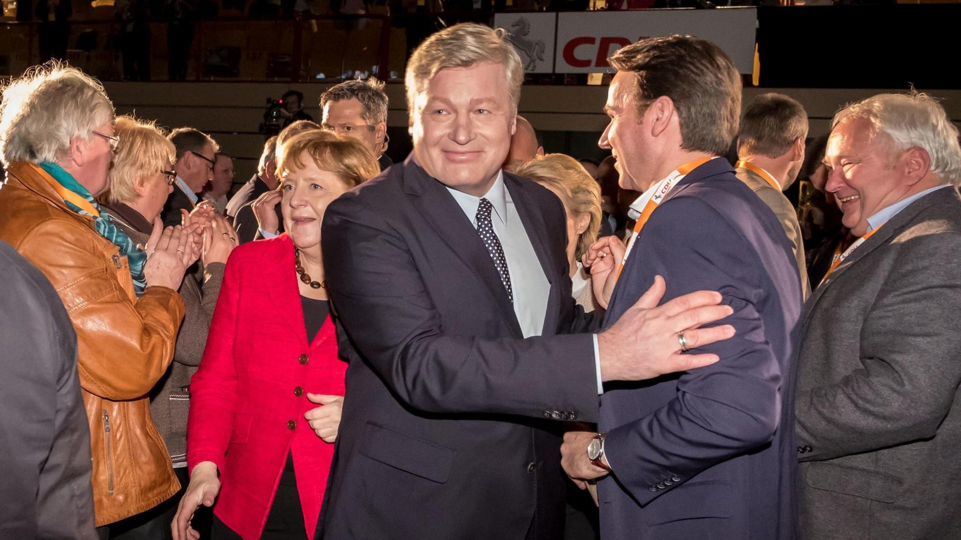 Bundeskanzlerin Angela Merkel (CDU, Mitte links in Rot) und der neue Landesvorsitzende der CDU und Spitzenkandidat für die Ministerpräsidentenwahl in Niedersachsen, Bernd Althusmann (Mitte rechts), gehen am 26.11.2016 während des Landesparteitages der CDU in Hameln (Niedersachsen) durch die Delegierten.
