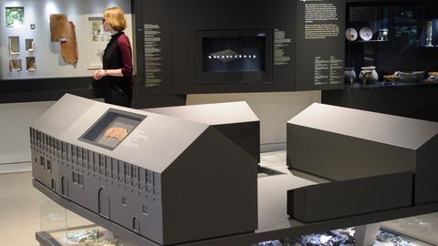 Ein Frau steht am 12.06.2014 in Mansfeld (Sachsen-Anhalt) während der Pressevorbesichtigung zur Lutherausstellung "Ich bin ein Mansfeldisch Kind" in der Ausstellung, im Vordergrund steht die Rekonstruktion des Anwesens der Familie Luther in Mansfeld.