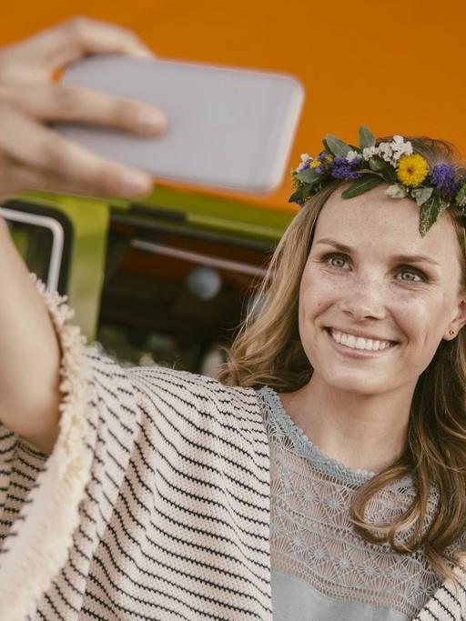 Eine Hippiefrau schießt ein Selfie vor ihrem Reisebus