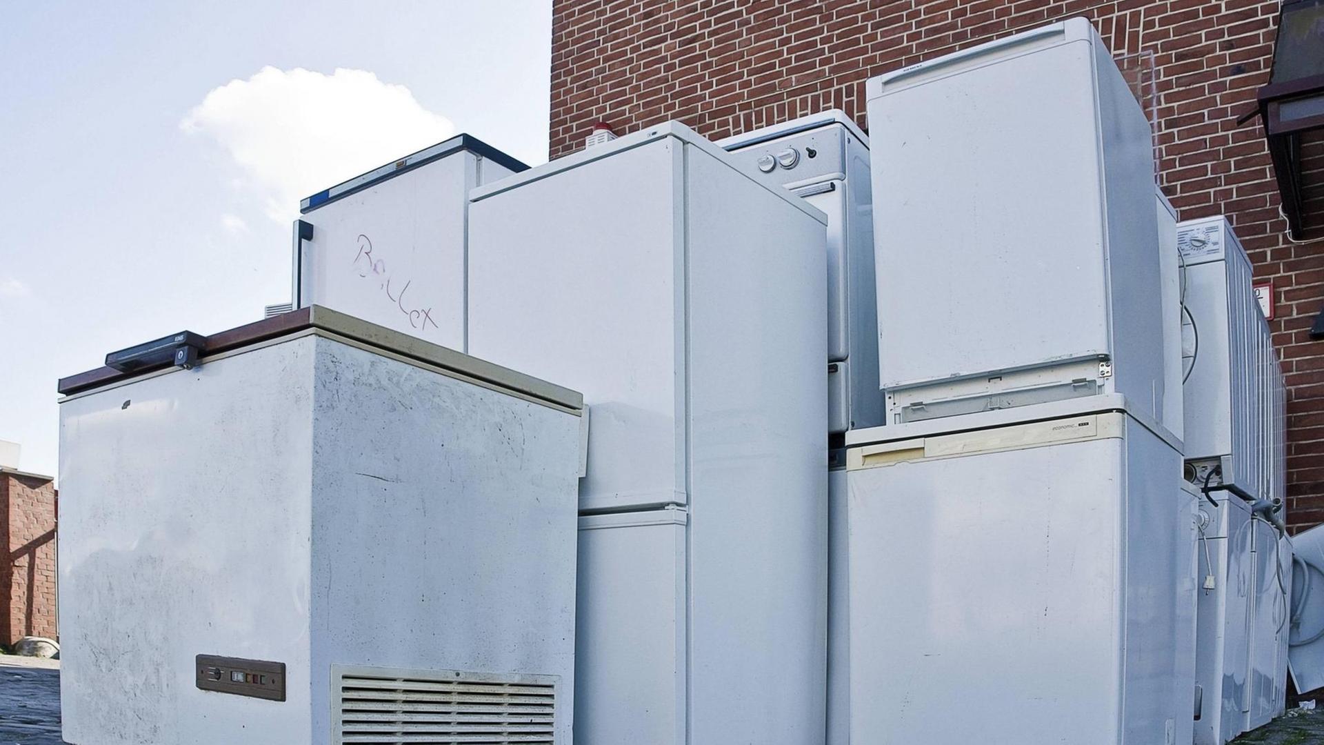 Alte Elektrogeräte stehen vor einer Backsteinwand zur Entsorgung bereit.