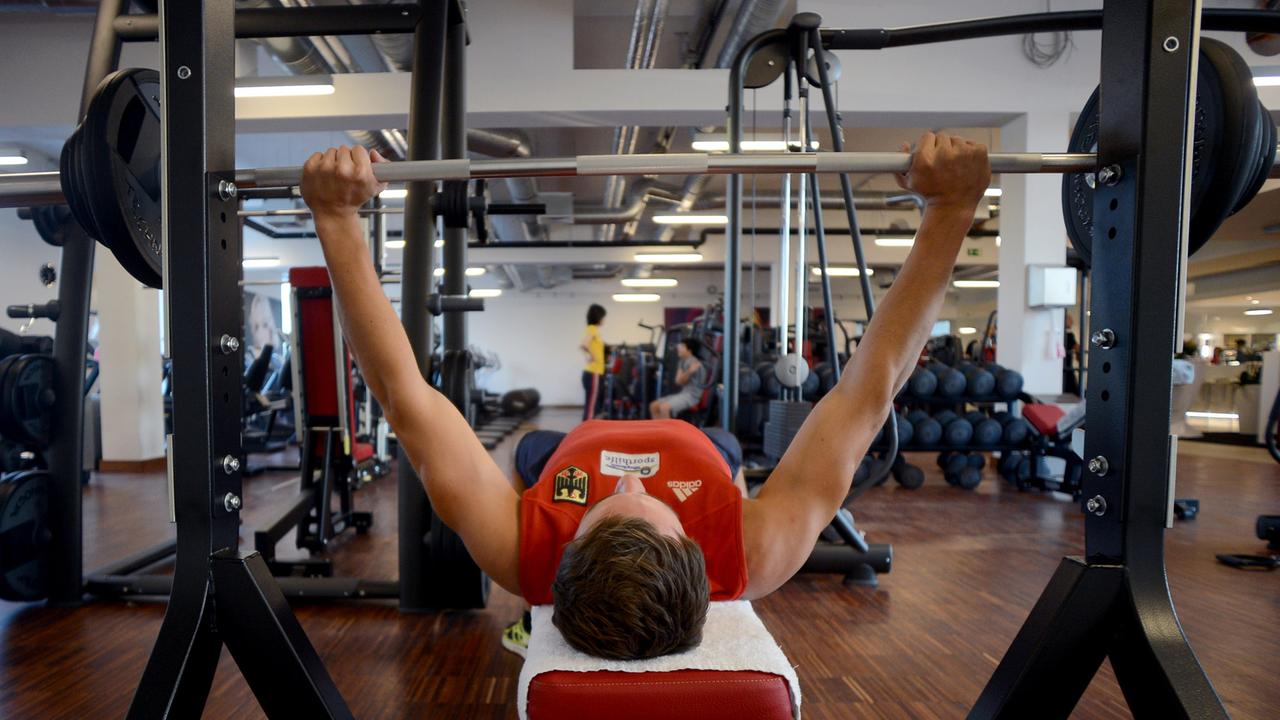 Fitnessstudios in Berlin. Ein Mann stemmt Gewichte