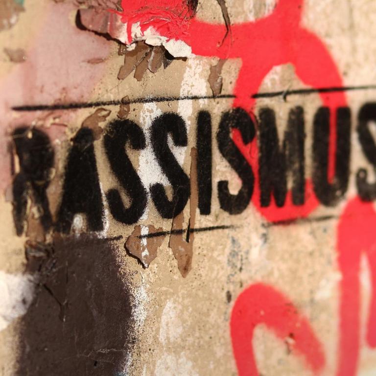 An eine beschmierte Wand ist das Wort "Rassismus" gesprüht worden.