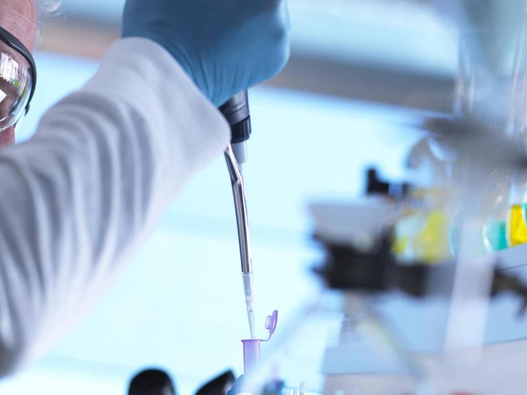 Ein Wissenschaftler nimmt per Pipette eine DNA-Probe