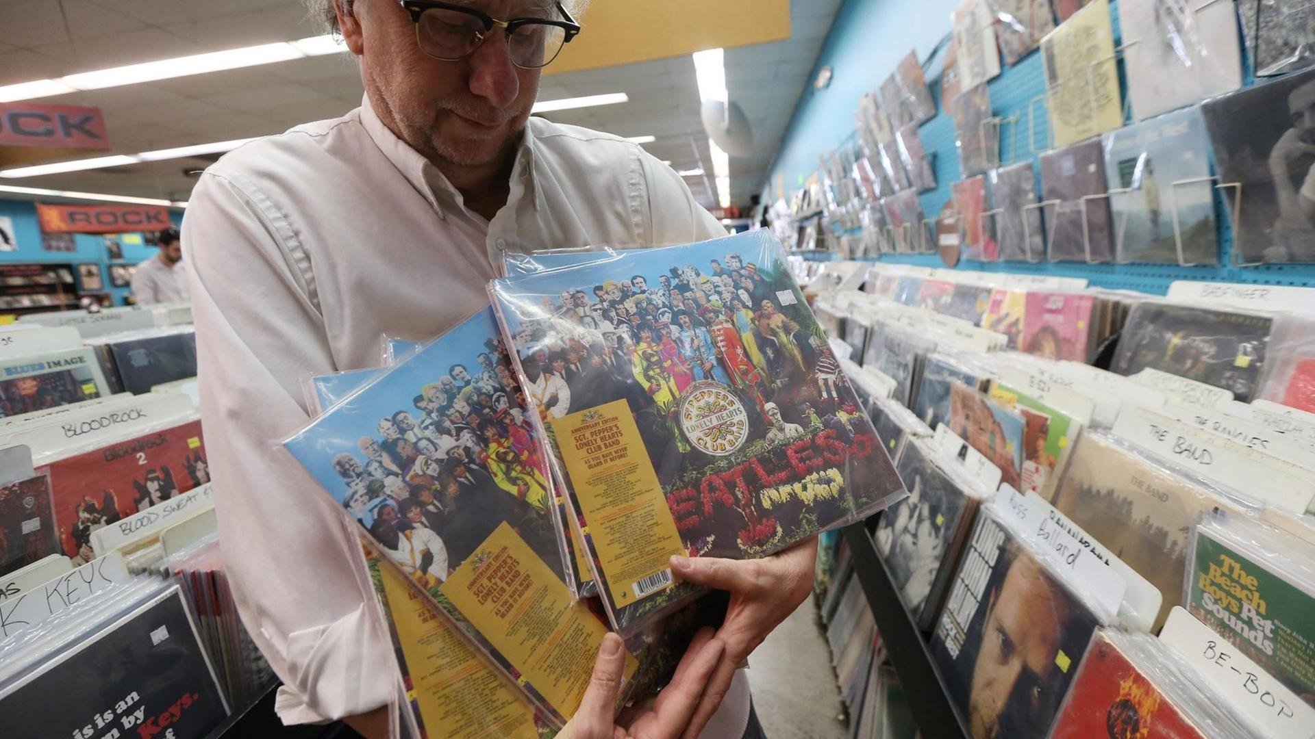 Ein Mitarbeiter eines Plattenladens in University City, Missouri mit der 50. Jubiläumsausgabe von "Sgt. Pepper's" von den Beatles.
