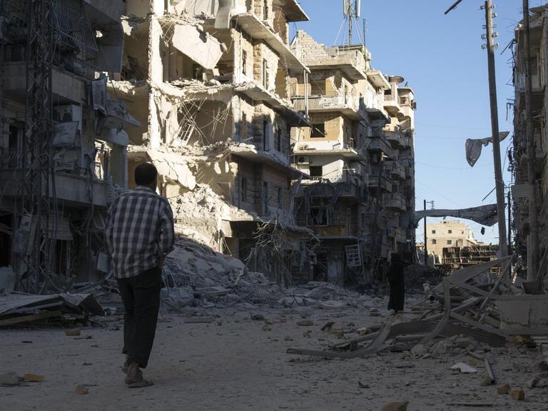 Ein Mann geht durch eine zerstörte Straße in Aleppo