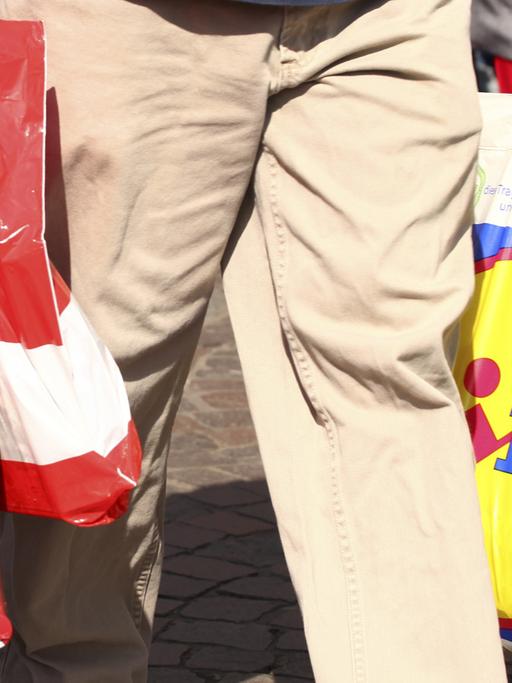 Ein Mann trägt Einkäufe in mehreren Plastiktüten
