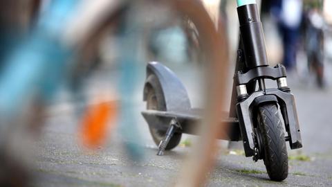 Ein E-Tretroller der Verleihfirma "Tier" steht in der Innenstadt hinter einem abgestellten Fahrrad.