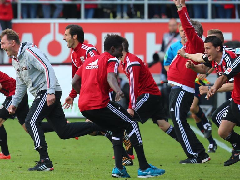 Die Spieler des FC Ingolstadt stürmen nach dem Abpfiff der Partie gegen RB Leipzig jubelnd über den Platz und feiern den vorzeitig gesicherten Bundesliga-Aufstieg. Die Spieler tragen schwarz-rote-Trikots. In erster Reihe jubelt auch Trainer Ralph Hasenhüttl