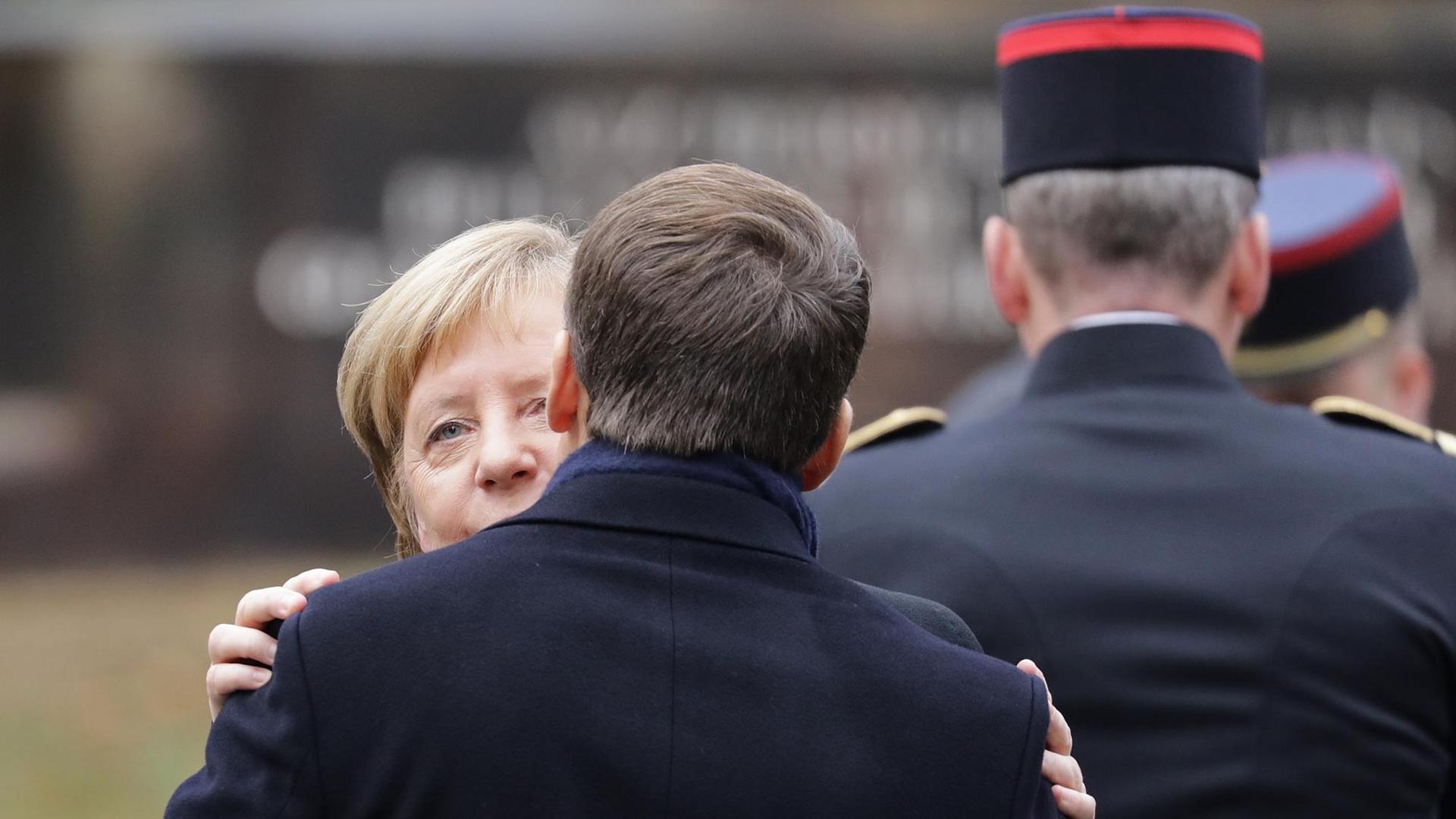 Bundeskanzlerin Merkel und Frankreichs Präsident Macron begrüßen sich.