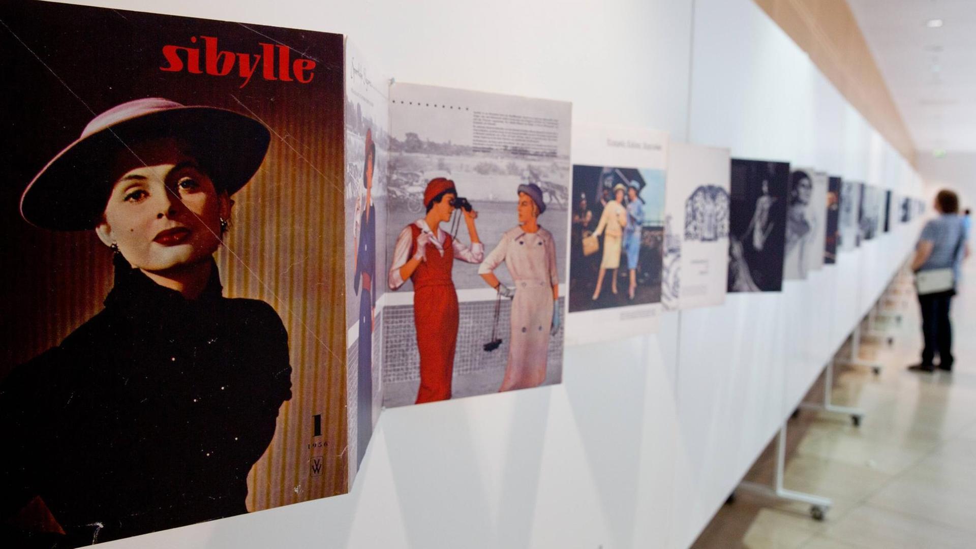 Eine Ausstellung zur DDR-Zeitschrift "Sibylle" im Willy Brandt Haus in Berlin im Juni 2019. Vergrößerte Auszüge von Exemplaren der Zeitschrift, hier mit dem Schwerpunkt Damenmode, werden von Besuchern betrachtet.