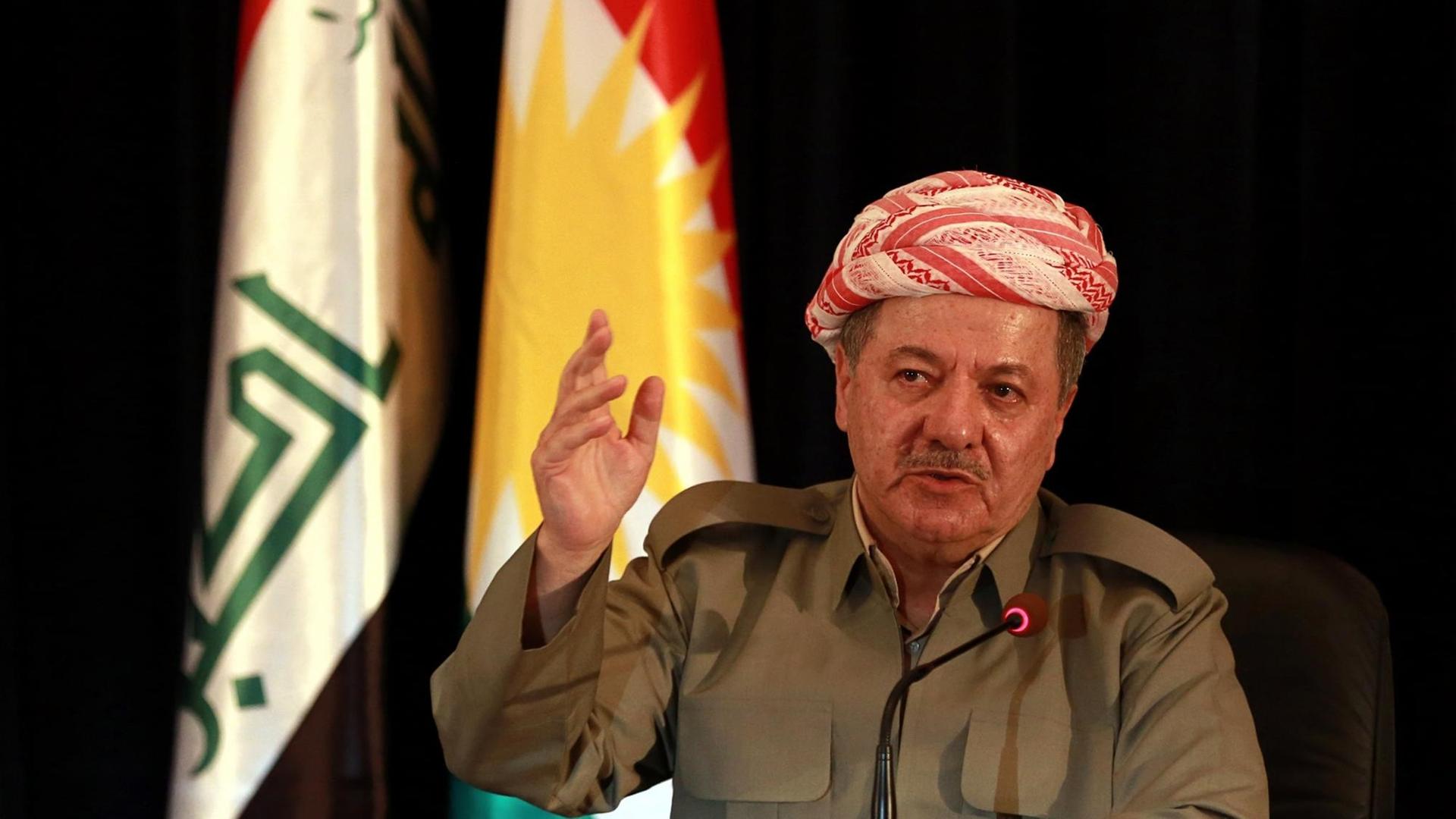 Der Präsident der kurdischen Minderheit im Irak, Massud Barsani spricht in Erbil sitzend in ein Mikrofon und gestikuliert mit seiner erhobenen rechten Hand.