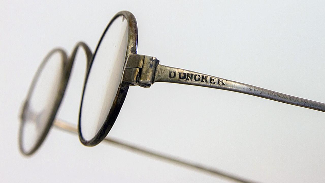 Nahaufnahme einer alten Brille, auf deren Bügel der Name "Duncker" eingeprägt ist.