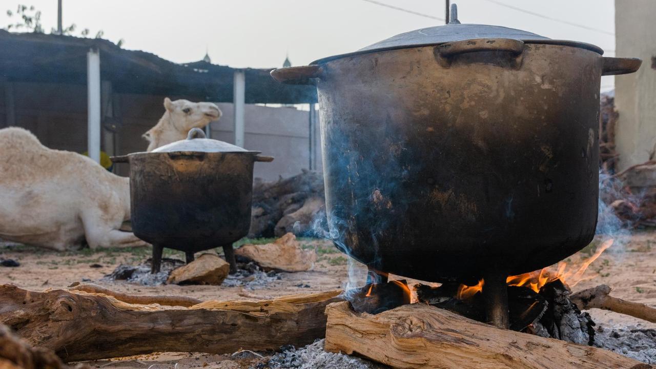 Kochtöpfe auf offenem Feuer und ein Kamel in einem von Toubas Hinterhöfen