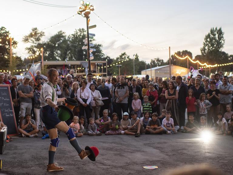 Besucher des Zürcher Theater Spektakels verfolgen die Vorführung eines Strassenkünstlers auf der Landiwiese in Zürich.