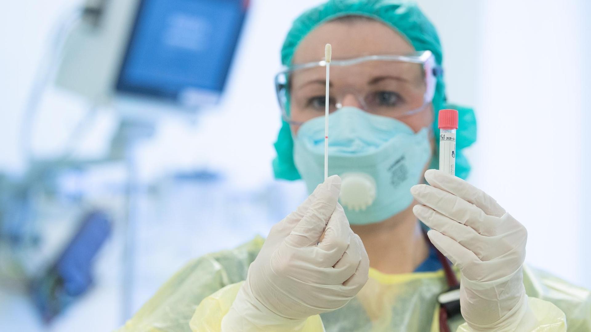 Eine Krankenschwester legt auf der Isolierstation für Coronavirus-Behandlungen ihre Schutzkleidung an bevor sie ein Patientenzimmer betritt.