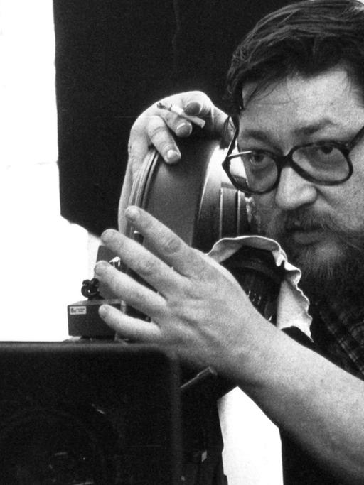 Schwarz-weißes Foto des Regisseurs Rainer Werner Fassbinder bei Dreharbeiten.