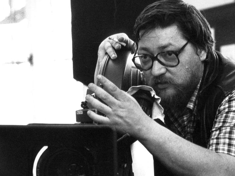Schwarz-weißes Foto des Regisseurs Rainer Werner Fassbinder bei Dreharbeiten.