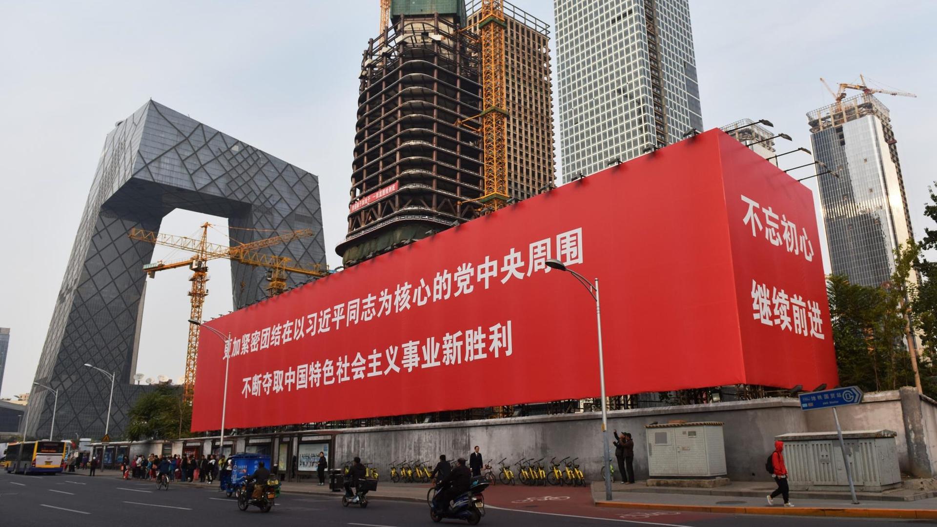 Eine großer Werbekubus in Peking vor eine großen Baustelle.