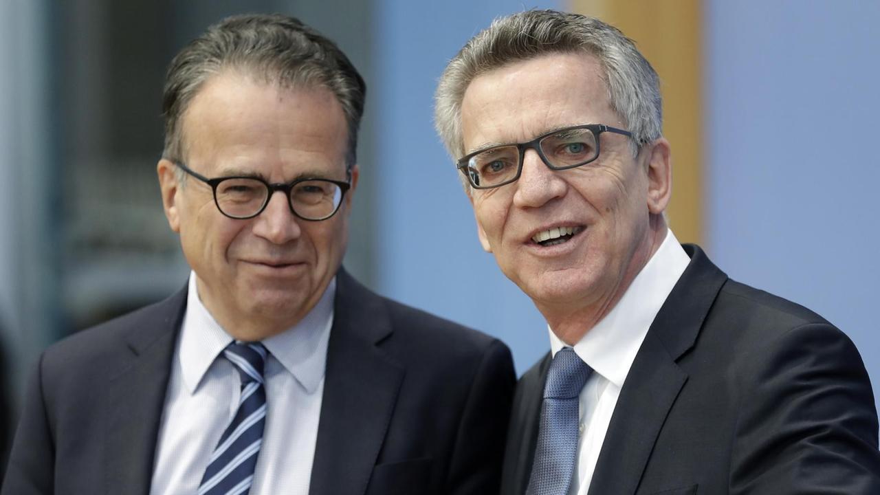 Bundesinnenminister Thomas de Maizière (r.) und BAMF-Chef Frank-Jürgen Weise schauen gut gelaunt in die Kamera. De Maizière zeigt auch in die Richtung.