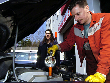 Ein Automechaniker füllt Öl in einen Motor.