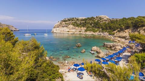 Liegen und Sonnenschirme stehen für Touristen am Anthony Quinn Bay auf Rhodos bereit.