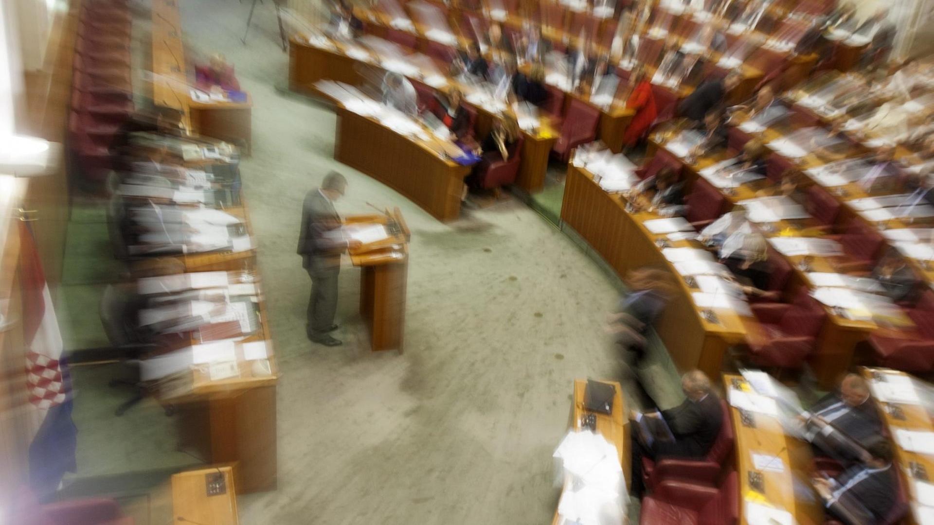 Ein mit besonderem Lichteffekt aufgenommenes Bild des kroatischen Parlaments in Zagreb. Die Sitzreihen mit den Abgeordneten und das Rednerpult sind verschwommen zuzu sehen. Ein mit besonderem Lichteffekt aufgenommenes Bild des kroatischen Parlaments in Zagreb. Die Sitzreihen mit den Abgeordneten und das Rednerpult sind verschwommen zuzu sehen.