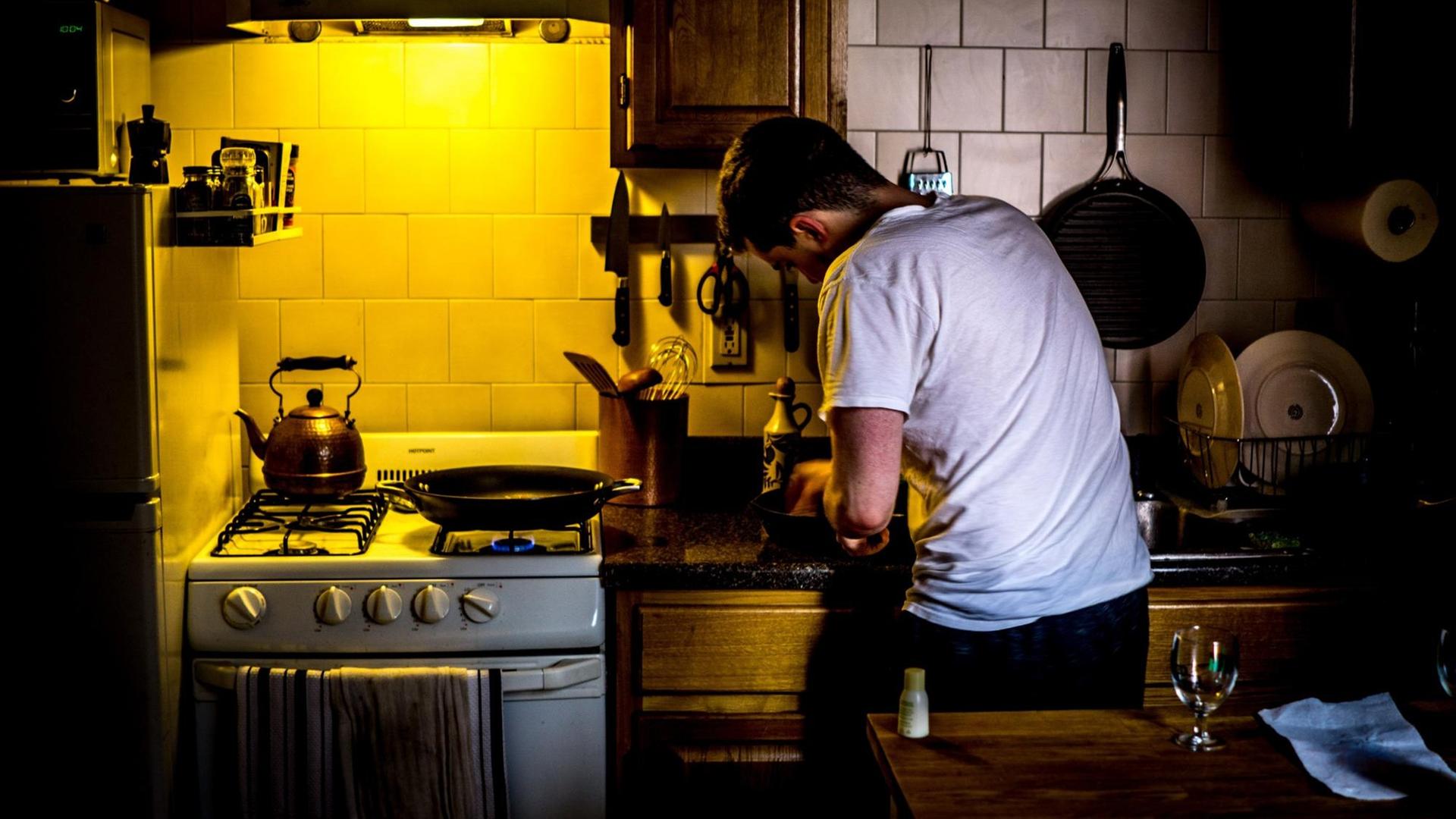 Das Bild zeigt einen Mann in einer kleinen Küche. Food Podcasts sind besonders bei Hobbyköchen beliebt – auch als Nebenbeibeschallung in der Küche.