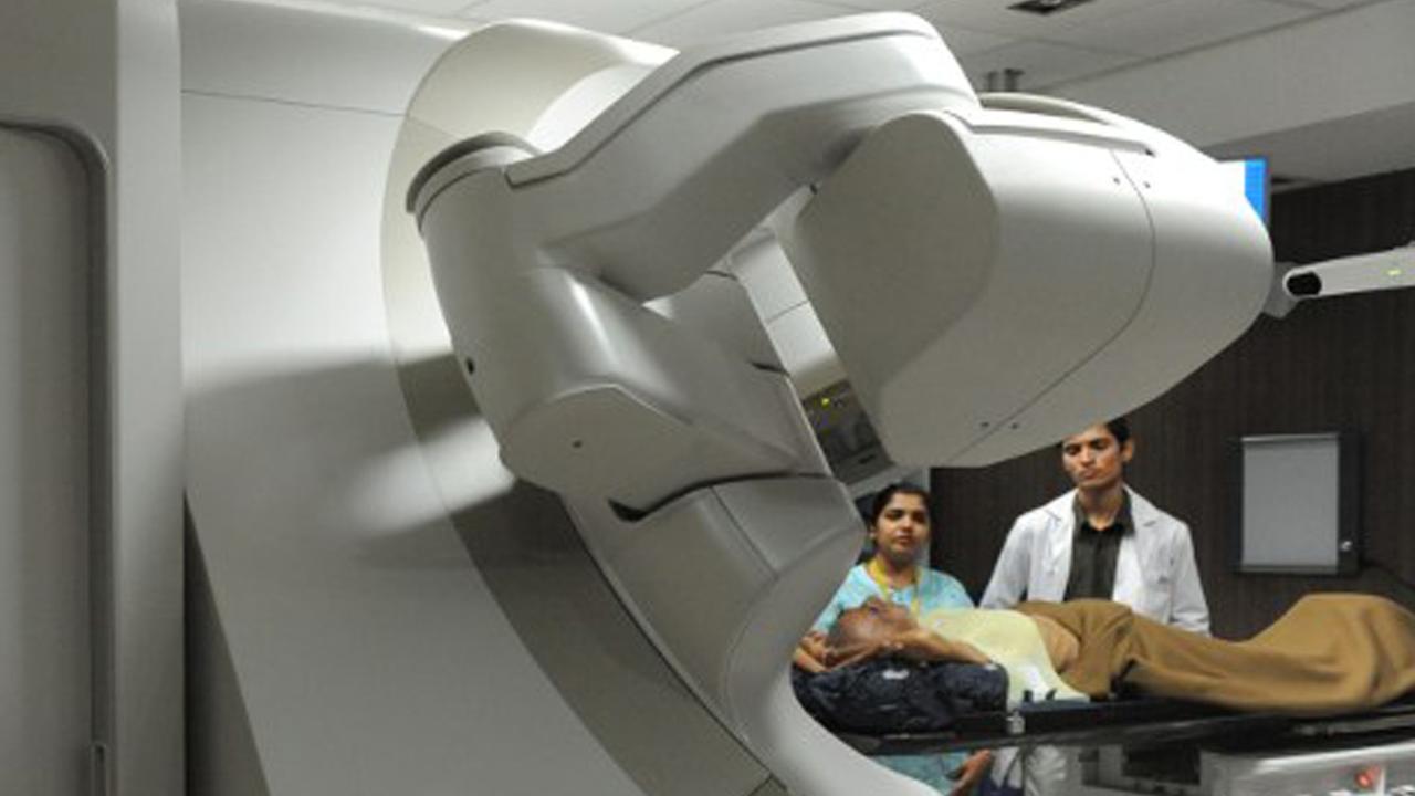 Zwei Ärzte und eine Patientin in einem Raum mit einem Bestrahlungsgerät