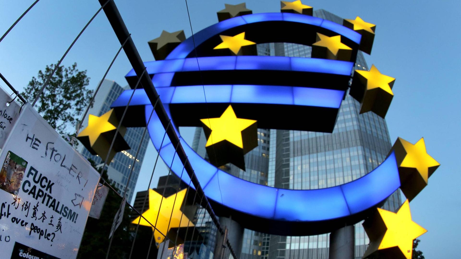 Das Eurozeichen vor der Europäischen Zentralbank (EZB) in Frankfurt/Main mit Protestplakat